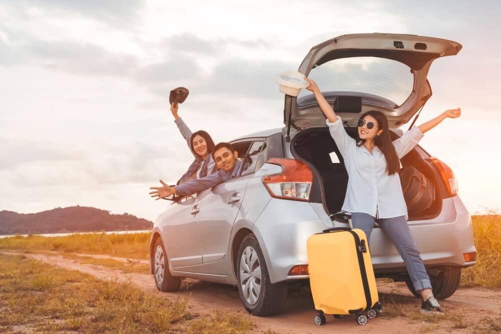 Happy travelers by the car